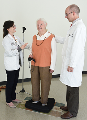 Timothy Hullar, MD, (right) and medical student Miranda Colletta help patient Audrey Miller prepare for a balance test. Older adults with hearing loss appeared to perform better on balance tests with both hearing aids on, according to Hullar’s research. 