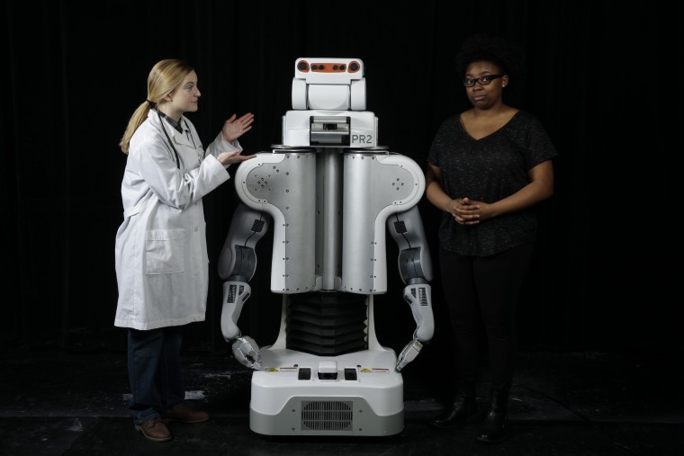 Doctor and patient standing next to robot.