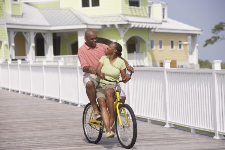Older couple riding bicycle on boardwalk