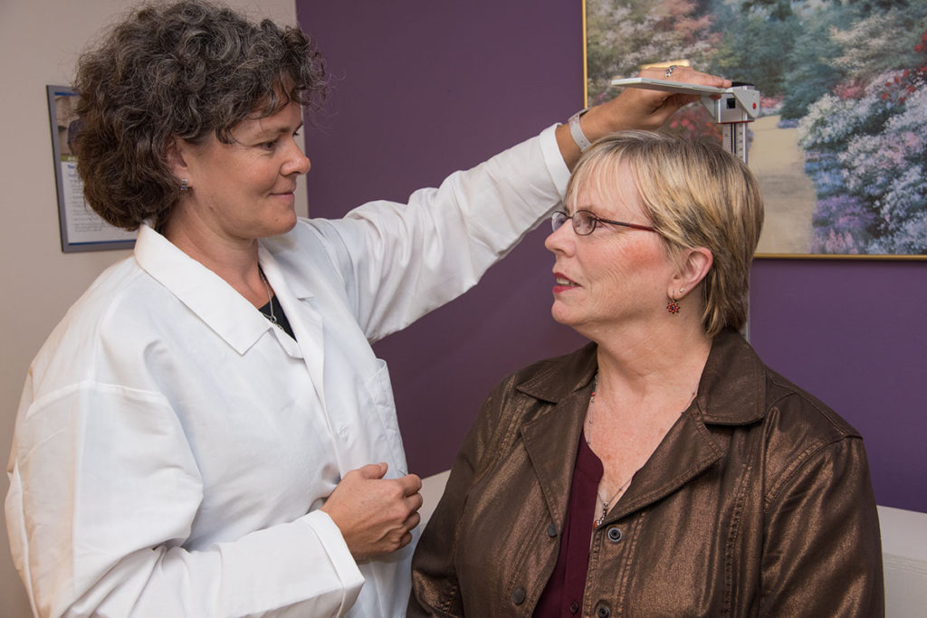 Bettina Mittendorfer (left) measures Mary Akin's height to calculate her body mass index, which is a ratio of height to body weight. Akin has been part of a study aimed at helping women lose weight and determining the effects of a high-protein diet on weight loss. The research team found that those who ate a high-protein diet to lose weight didn't get the metabolic benefits seen in women who lost weight on a lower-protein diet. (Photo: Robert Boston/School of Medicine)