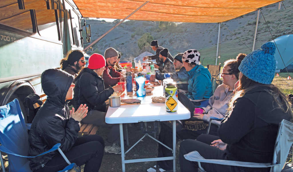 Under a canopy hanging from the ­“Science Bus,” researchers eat their meals and discuss excavation details. Their nearby tent camp (see pg. 27) allows the team to live in much the same way as the nomads who once populated the area. (Photo: Thomas Malkowicz)