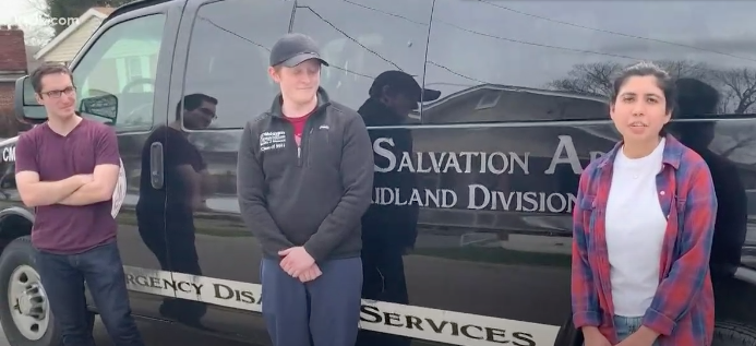 Three students stand in front of Salvation Army van