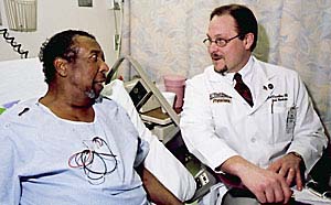 Mark S. Thoelke, MD, clinical director of the division of hospitalist medicine, talks with patient Willie E. Cox.