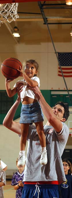 Basketball player Mike Grunst gives a boost to sports clinic participant Ke'ala O'Connell, daughter of assistant men's basketball coach Kevin O'Connell.
