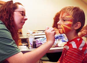 Student Christine Holladay paints the face of Liam Perry at a demonstration of makeup used for stage performances.