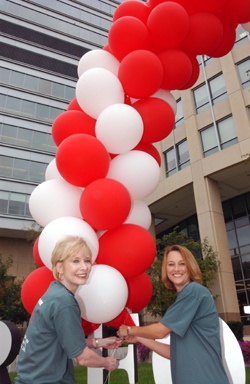 (From left) Glenda Wiman, assistant dean and assistant vice chancellor for special programs, adjusts balloons with Cami Taylor, programs specialist, in front of the Center for Advanced Medicine.