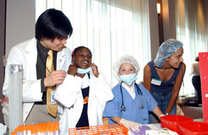 At the Kids Corner, children dress up like doctors.  Shown from left to right are Walter Chan, a fourth year medical student; party guests  Alexis Dallas and T.J. Lucas; and Monica Ghe, a first year medical student.