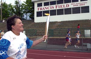 Teri Clemens carries the torch on Bushyhead Track on Francis Field as part of her leg of the Global Torch Relay.