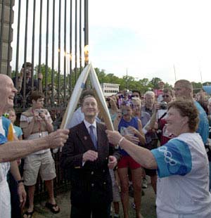 As part of the Global Olympic Torch Relay on June 17 at Francis Field, E. Desmond Lee passes the flame to former Bears volleyball coach Teri Clemens as Chancellor Mark S. Wrighton looks on.
