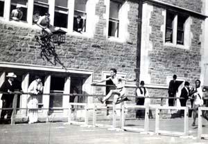 Athletes in the 1904 Olympic Games run the hurdles next to the Francis Gymnasium.