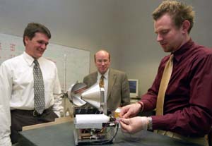 Michael Swartwout (left), Keith Bennett (middle) and Jared Macke work with the mini-sattelite *Bandit* in a simulated docking exercise.