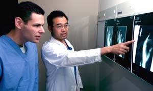 Surgeon Thomas H.H. Tung, M.D. (right), and Michael Cohen review images of a fractured thumb after extensive reconstructive surgery, which entailed fusing the bones together after a machine crushed the patient's thumb. Tung says Cohen 