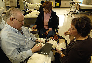 (From left) Nelson Flagg and his wife, Rose, work with Vicki Friedman, director of the School of Medicine's Medical Photography, Illustration and Computer Graphics, to paint tiles while Nelson is treated at the Siteman Cancer Center.