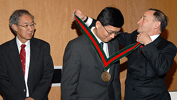 Chancellor Mark S. Wrighton (right) installs Lihong Wang, Ph.D., as the Gene K. Beare Distinguished Professor of Biomedical Engineering, while Frank Yin, M.D., Ph.D., looks on.