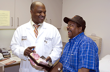 Arnold Bullock, M.D., talks with patient Joseph Griffin while showing a model of the prostate. Bullock has been 