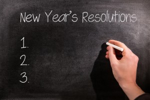 A hand writes new year's resolutions on a blackboard