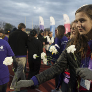 student hands flowers to cancer survivors