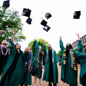 Students toss their mortar boards in the air