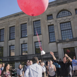 people launch a red weather balloon into the sky