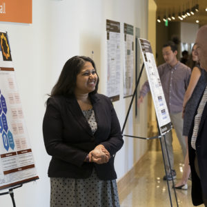 two people talk in front of a research poster