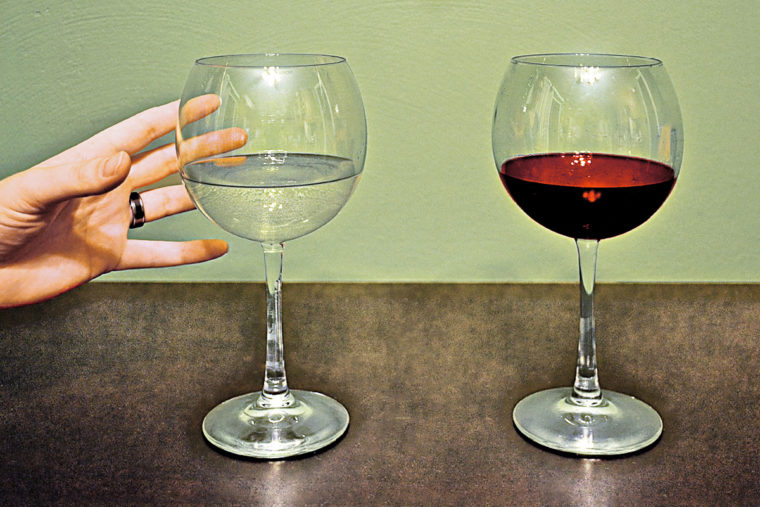 A hand reaching for two glasses of wine.