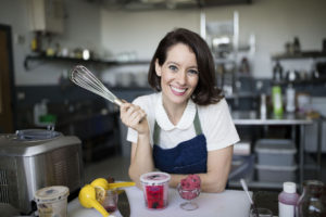Deborah Gorman of Sorbabes holds a wire whisk and smiles as she leans over a scoop of Sorbabes ice cream.