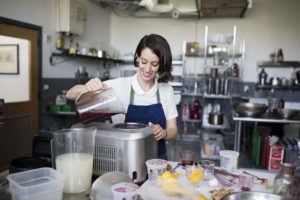 Deborah Gorman, in a blue apron, pours sorbet mixture into an ice cream maker.