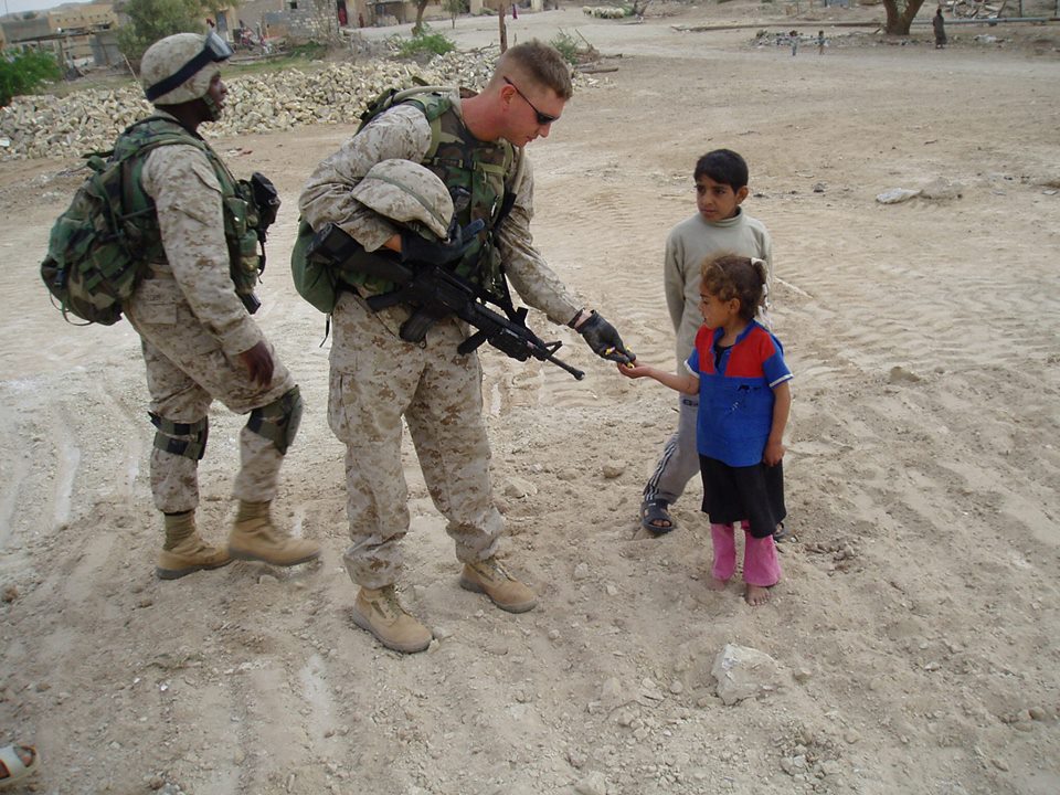 Petersen hands out Jolly Ranchers to Iraqi children in 2003. 