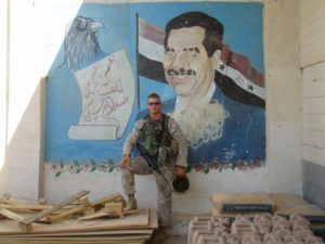 Petersen stands in front of a mural of toppled Iraqi dictator Saddam Hussein. 