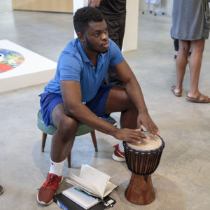 student plays a bongo in an art museum