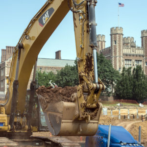 a digger claw lifts dirt in front of Brookings Hall