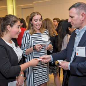 Alumni, parents and current students gathered for networking opportunities at a downtown Washington, D.C., event co-hosted by the WashU Government and Public Policy Network and the WashU Defense, Aerospace and National Security Network last summer. WashU parent Col. Eric Heist (right), MBA ’92, hands his business card to undergraduate engineering students Alaina Fierro (left) and Eden Livingston. (Photo: Andres Alonso)