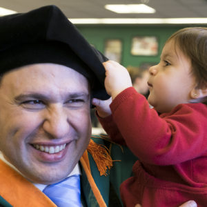child with dad in graduation gown