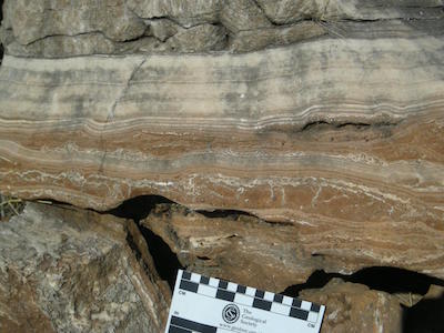 Field photograph of massive flowstone layers from one of the South African hominin caves, with red cave sediments underneath