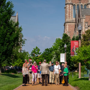 Group of people standing while listening to tour guide speak on WashU campus.
