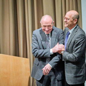 Dean David Perlmutter embraces Philip Needleman on stage.