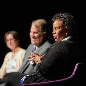 Three people sit on a stage as part of a panel discussion.