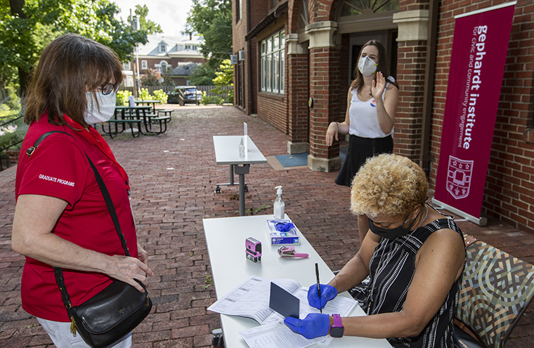 Jackie Lorrainne (right), associate university librarian, notarizes the ballot of Connie Fahey, who works at Olin Business School, on July 22. Lindsay Gassman of the Gephardt Institute’s voter engagement effort, stands nearby. (Photo: Joe Angeles/Washington University)