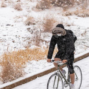 student bicycling during snowfall