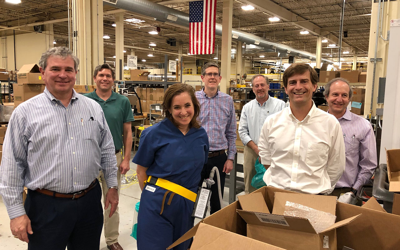 Nick Colarelli, MSEE ’86 (left); Jennifer DeLaney, MD ’97 (center); and Bret Bauer (right), president of Hunter Engineering, met with the engineering team at Hunter Engineering to inspect the revised powered air-purifying respirators prior to submitting them for NIOSH approval. The CDC rates the device to be at least two-and-a-half times better at preventing exposure than an N-95 mask. (Courtesy photo)
