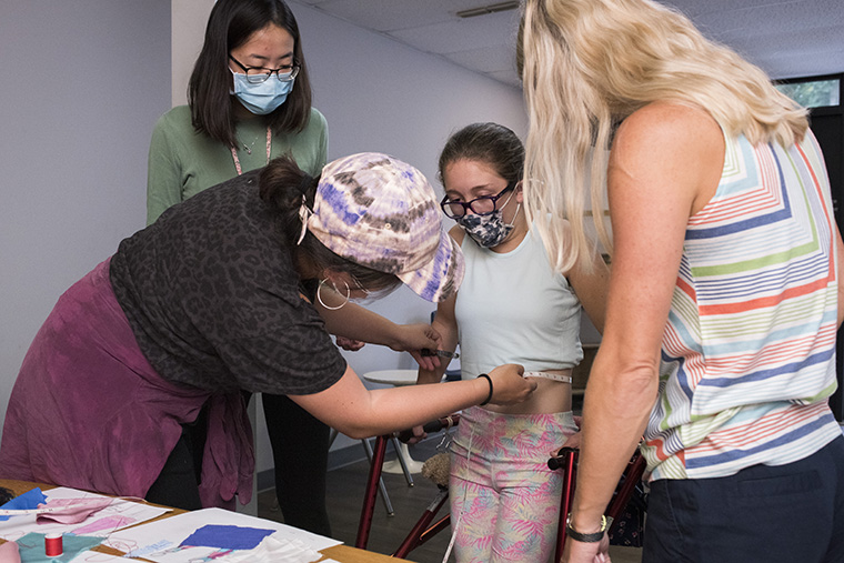 Maxine Roeder (left) takes the measurements of her model Olivia Kallaos with help from Shelei Pan (second from left) and Olivia's mom Bonnie. (Photo: Carol Green/Washington University)