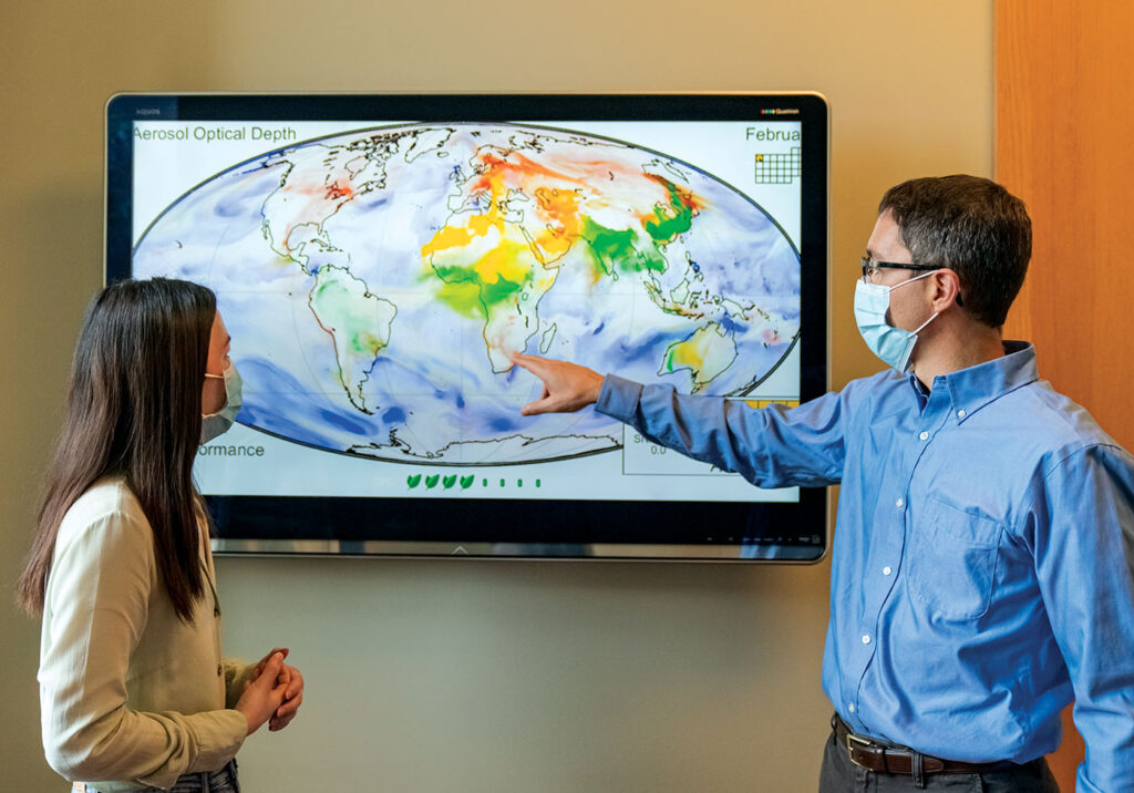 Randall Martin and PhD student Dandan Zhang (left) study a map showing the movement of smoke from wildfires in California. Particles emitted from the fires reached St. Louis in days. It takes just weeks for some atmospheric particles to traverse the globe. Mineral dust from the Sahara Desert, for example, provides nutrients for the Amazon. (Photo: Joe Angeles)