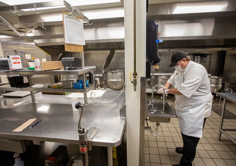 Image of an employee of University Dining Services washing his hands in a kitchen