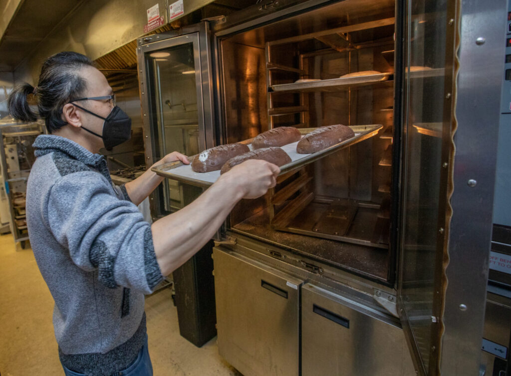 Raymond Yeh loads loaves of Chocolate Cherry bread into the oven