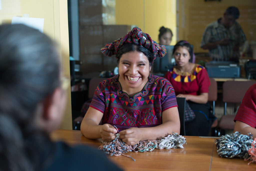 woman smiles while weaving yarn