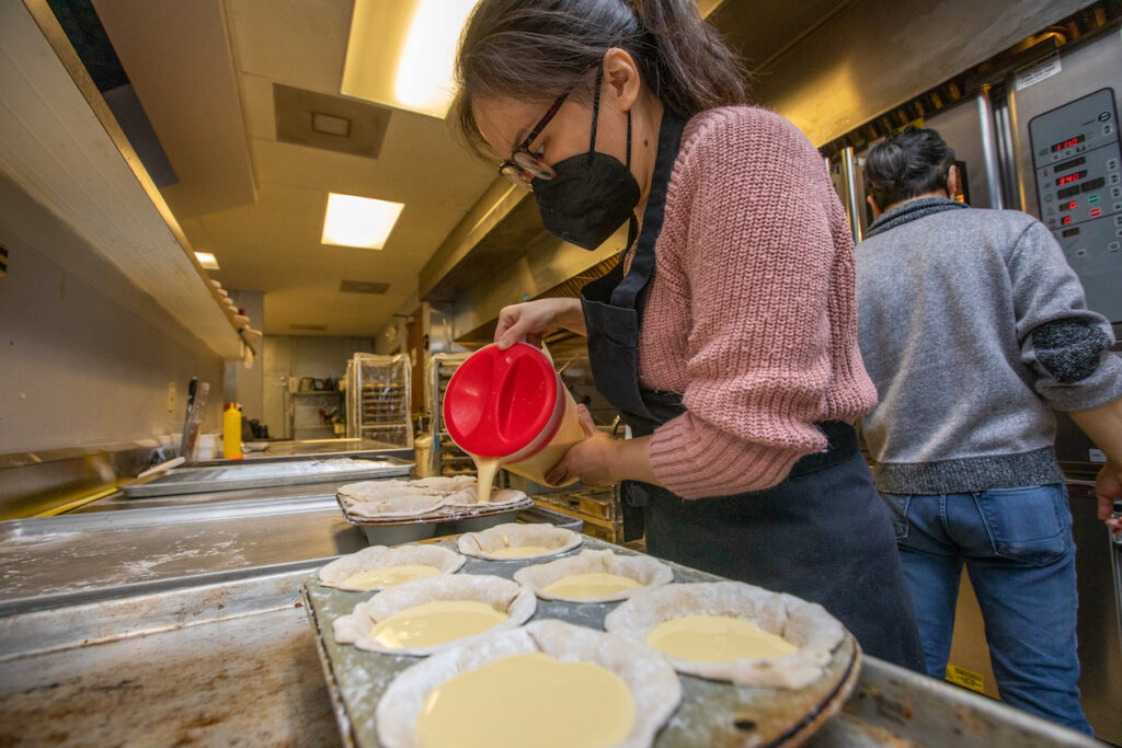 Leah Yeh prepares Pasteis De Nata (Known as the Portugese egg tart) for the oven. Raymond Yeh checks the ovens in the background.