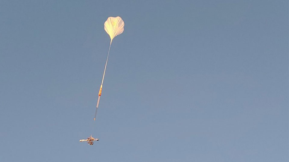 Large, translucent XL-Calibur balloon in the sky with the payload attached