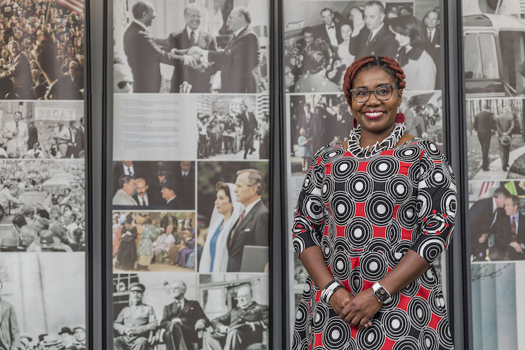 WashU alumna Imani Cheers in front of a collage of historical images.