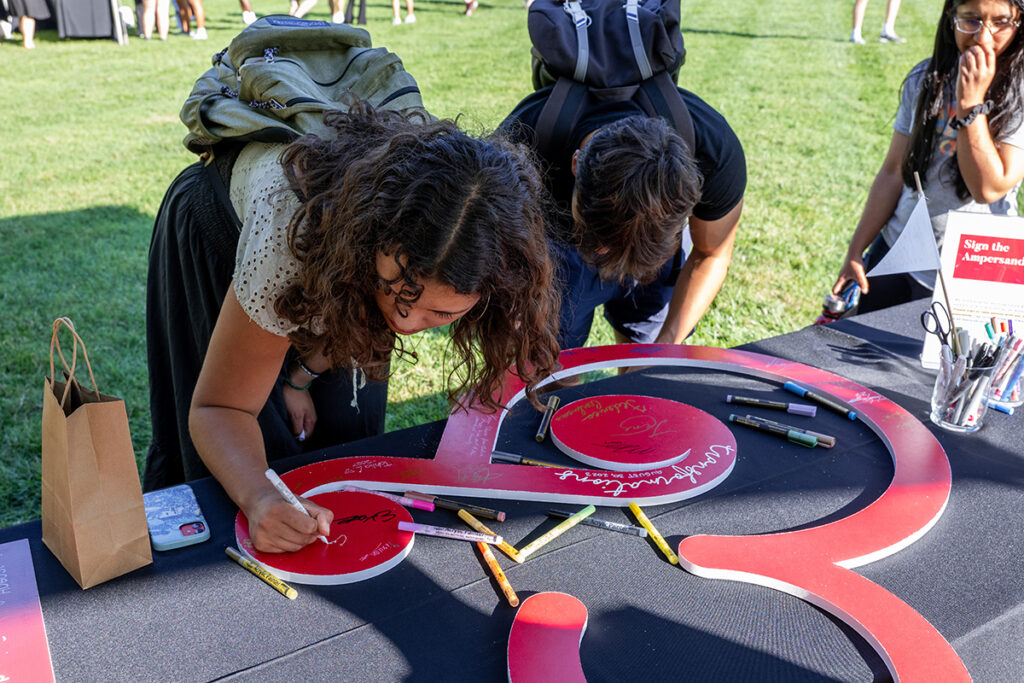Students sign a large red ampersand