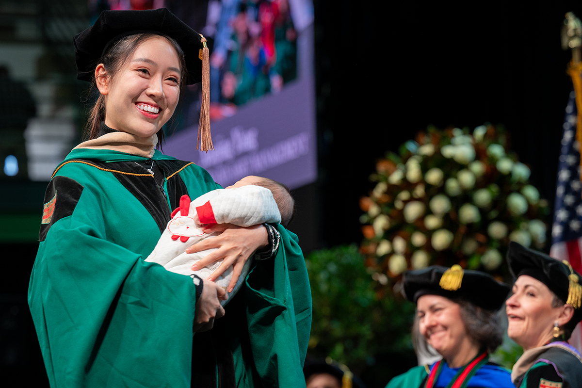 A proud graduate holds a baby 